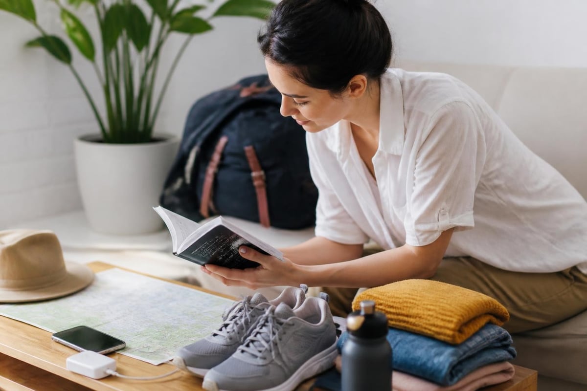 Traveller reading a travel guide while packing